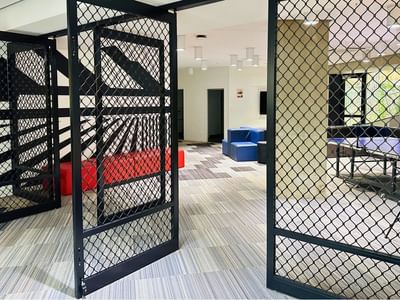 Black metal gates and game room with blue and red furniture at UniLodge Auckland City.