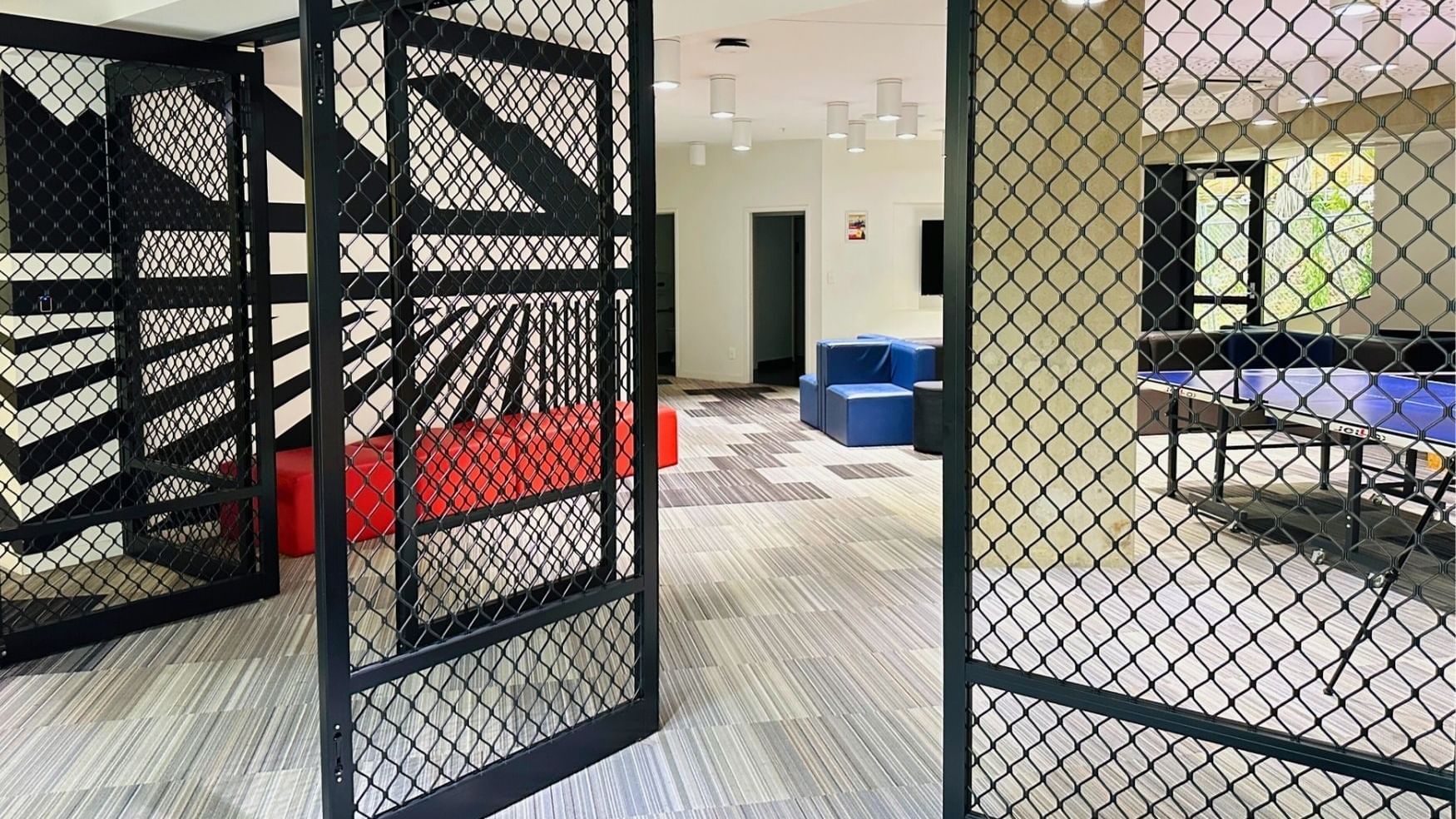 Black metal gates and game room with blue and red furniture at UniLodge Auckland City.