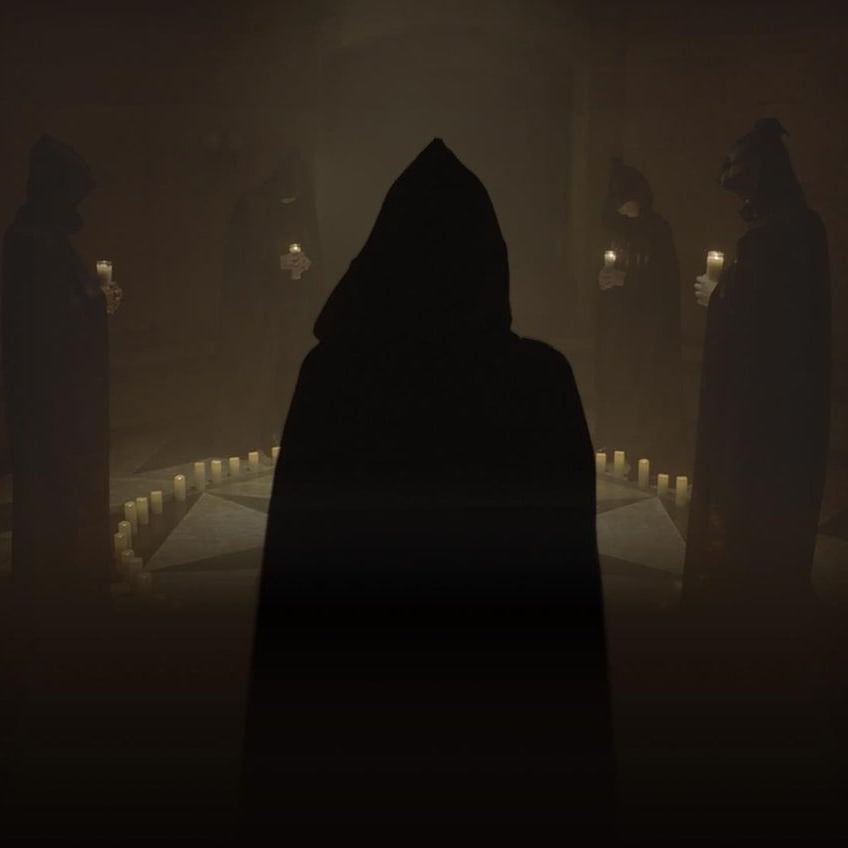 An image of a group of people wearing black cloaks and performing a ritual