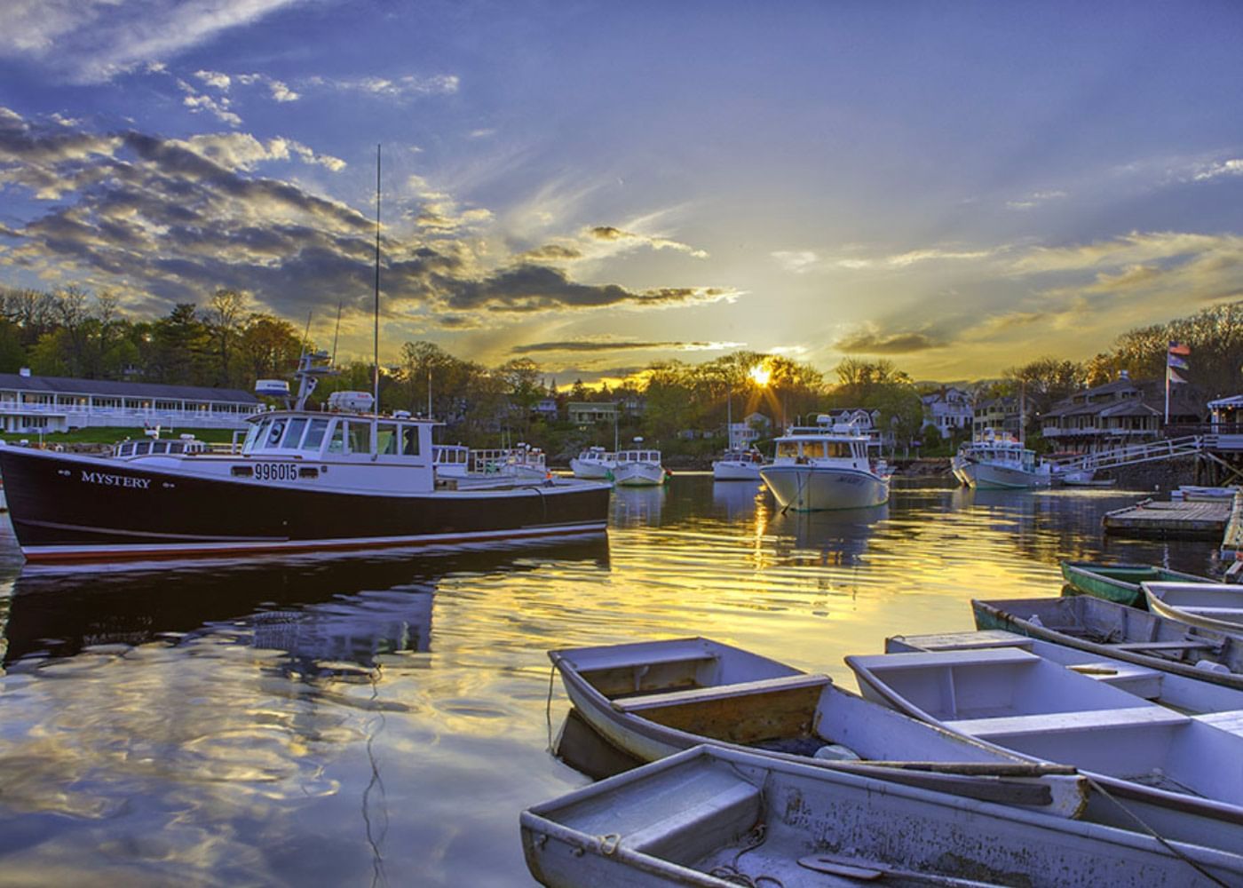 A serene harbor scene at sunset with boats docked in the water.