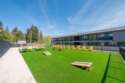 Cornhole boards on a green turf patio with picnic seating area at The Varsity South