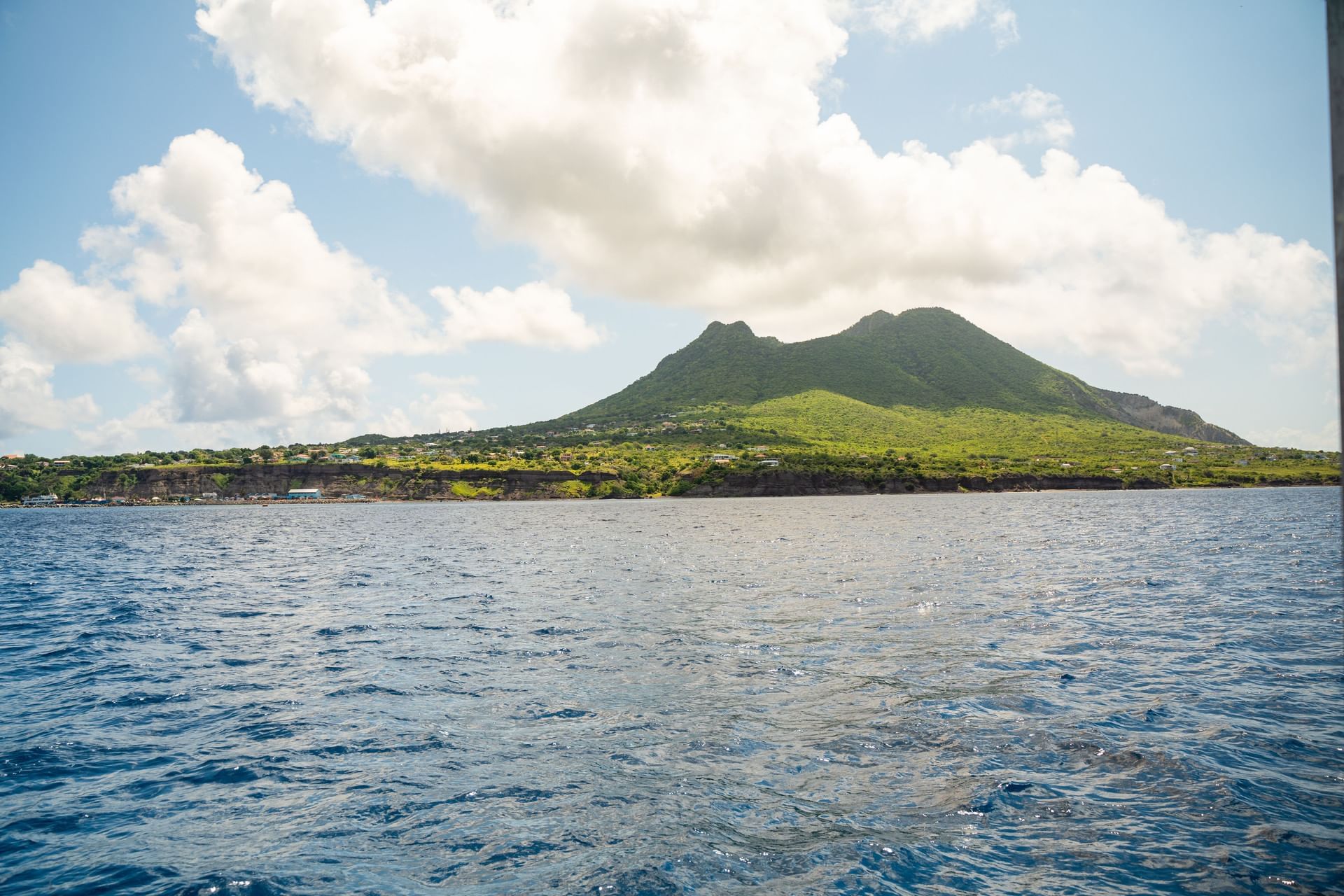 Panoramas of Mount Mazinga with lush green volcanic mountain slopes seen across deep ocean waters near Golden Rock Resort