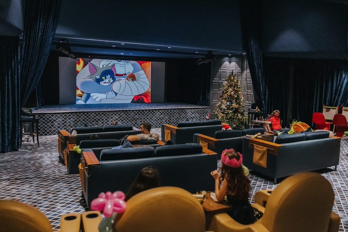 Cozy sofas arranged with a digital screen in the Screening Room at Paramount Hotel Dubai