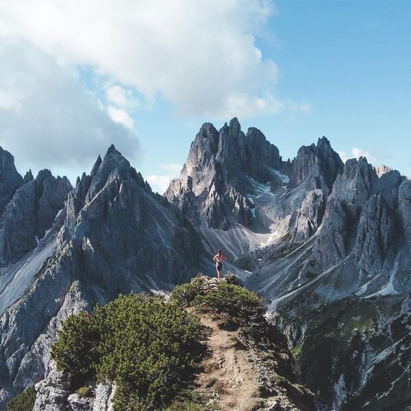 Person on mountain path with dramatic rocky peaks in the background near the Falkensteiner Hotels & Residences