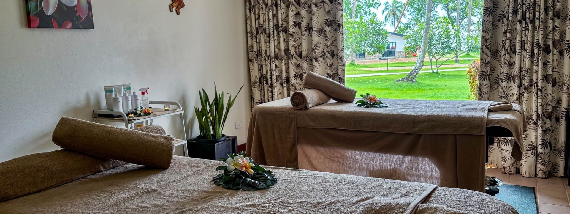 Massage beds by tropical curtains under a floral painting The Joy Spa at The Naviti Resort in Korolevu
