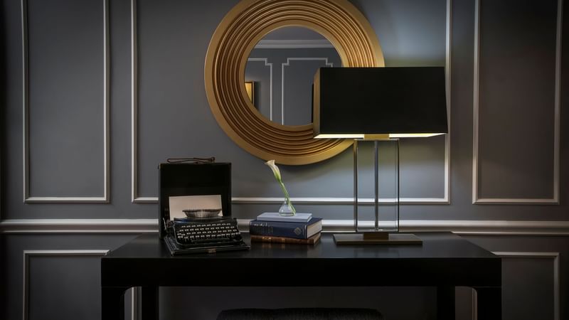 Typewriter, books, and table lamp on a table in Randolph's Suite at Warwick New York