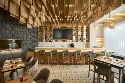 A beautifully illuminated luxury resort bar setup with sophisticated copper pendant fixtures.