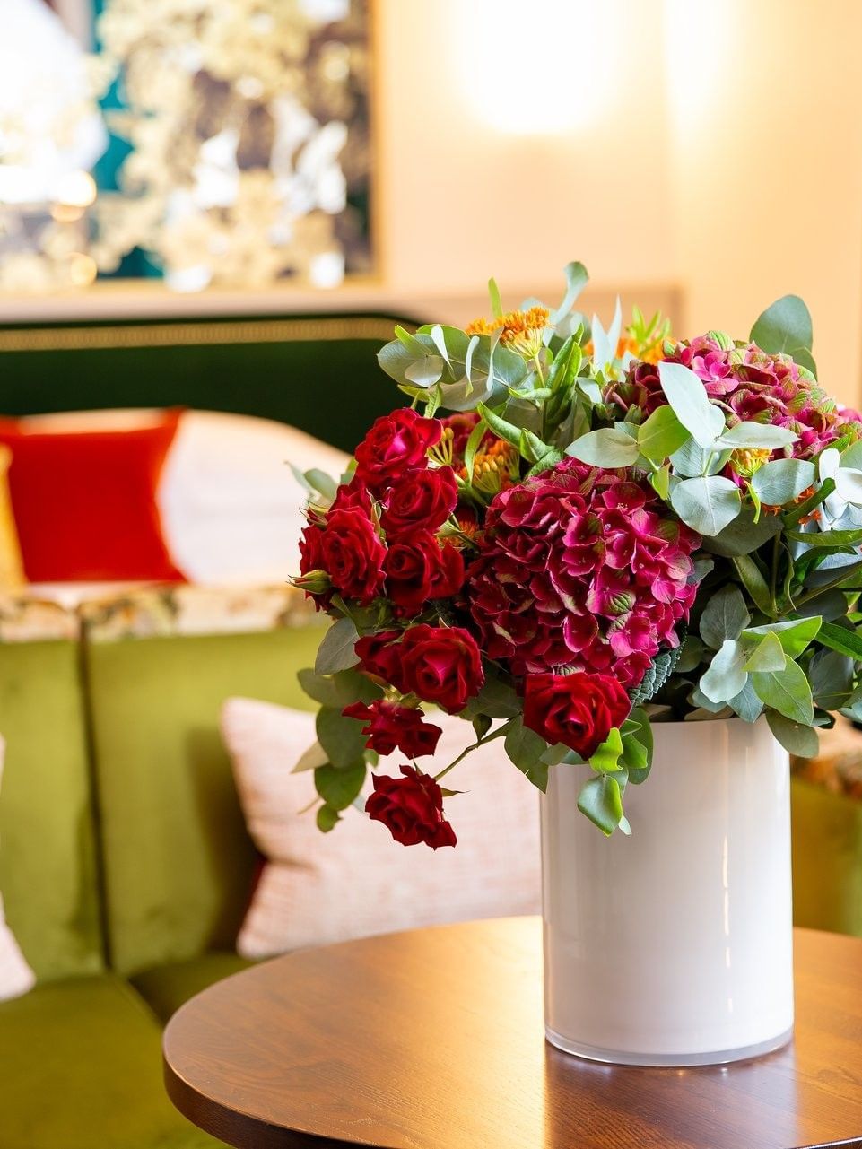Floral arrangement in a vase on a table by a green sofa in Deluxe King at The Capital Hotel, Apartments and Townhouse