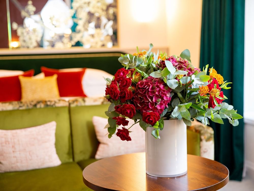 Floral arrangement in a vase on a table by a green sofa in Deluxe King at The Capital Hotel, Apartments and Townhouse