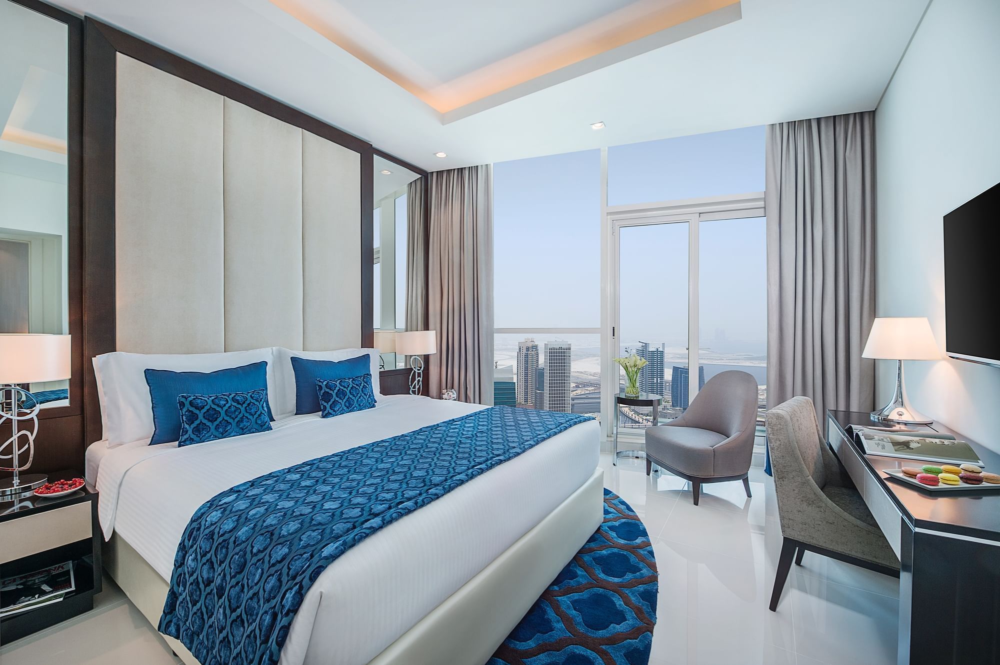 King-size bed by the window & a work desk in One Bedroom Suite at DAMAC Maison Distinction