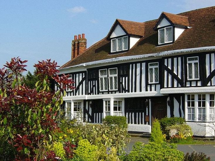 Exterior view of Marygreen Manor, featuring Tudor-style architecture and manicured gardens under a clear sky