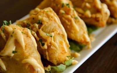 Golden fried appetizers drizzled with savory sauce on a long white platter at Clemson University Conference Center & Inn