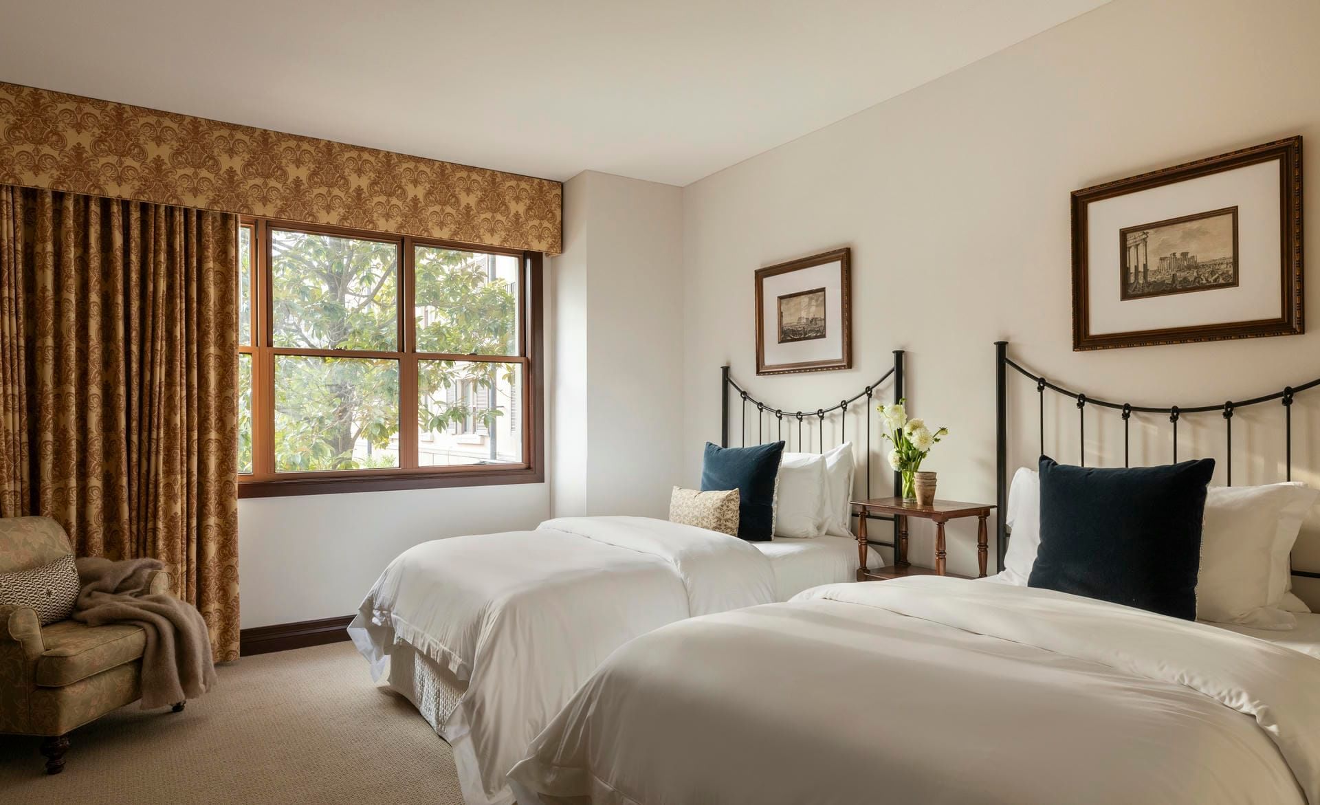 Two twin beds with black metal frames, white bedding, and navy accent pillows in a room at Hotel Granduca Houston