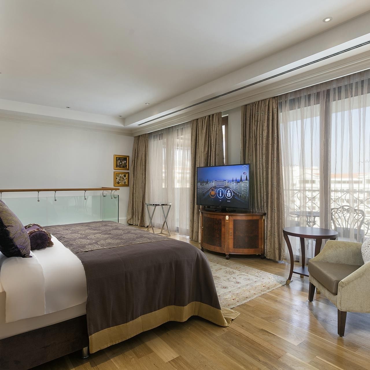 Спальня в большом двухуровневом люксе отеля Titanic Mardan Palace с просторной кроватью, креслом, телевизором и балконом