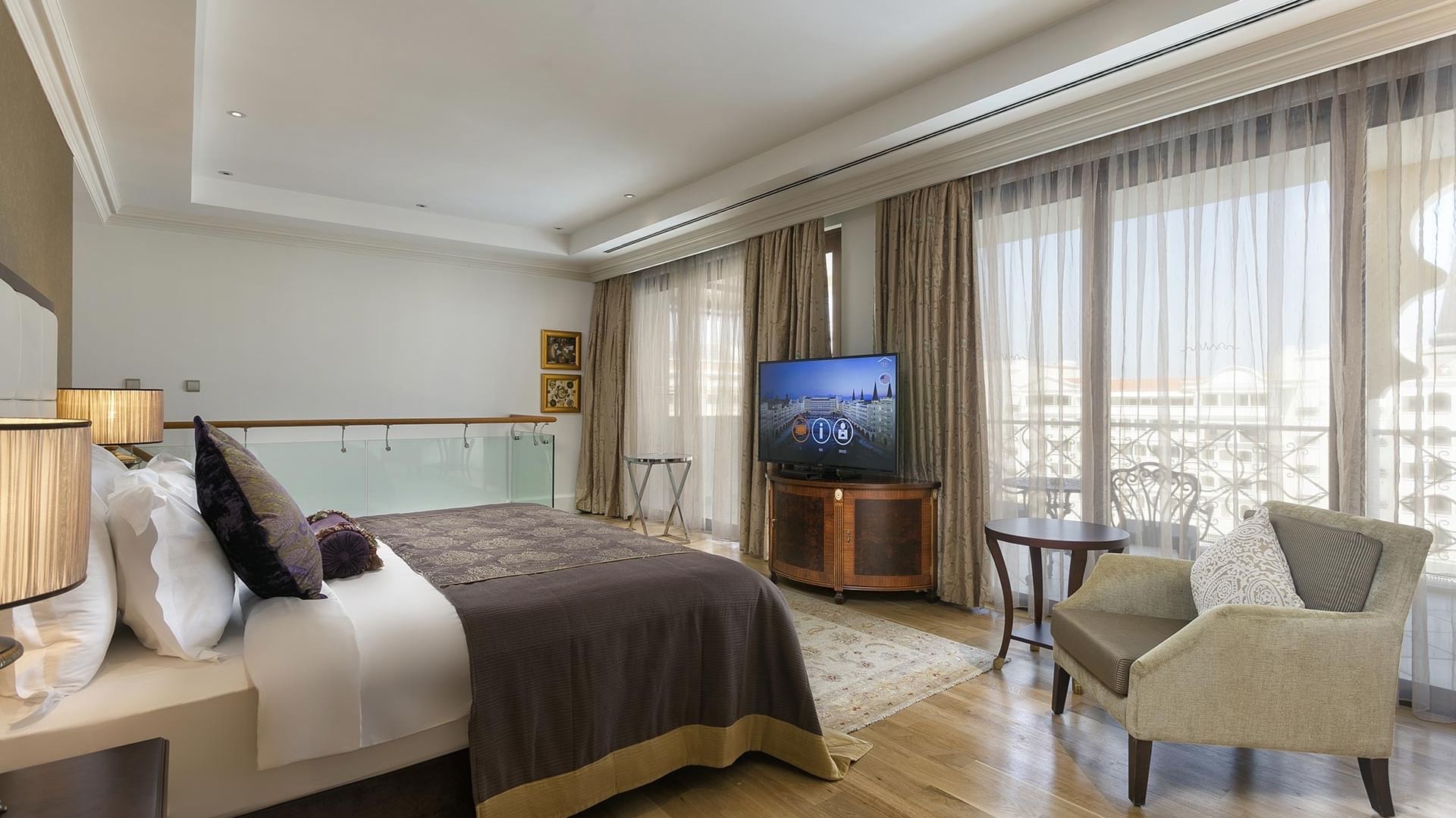 Спальня в большом двухуровневом люксе отеля Titanic Mardan Palace с просторной кроватью, креслом, телевизором и балконом