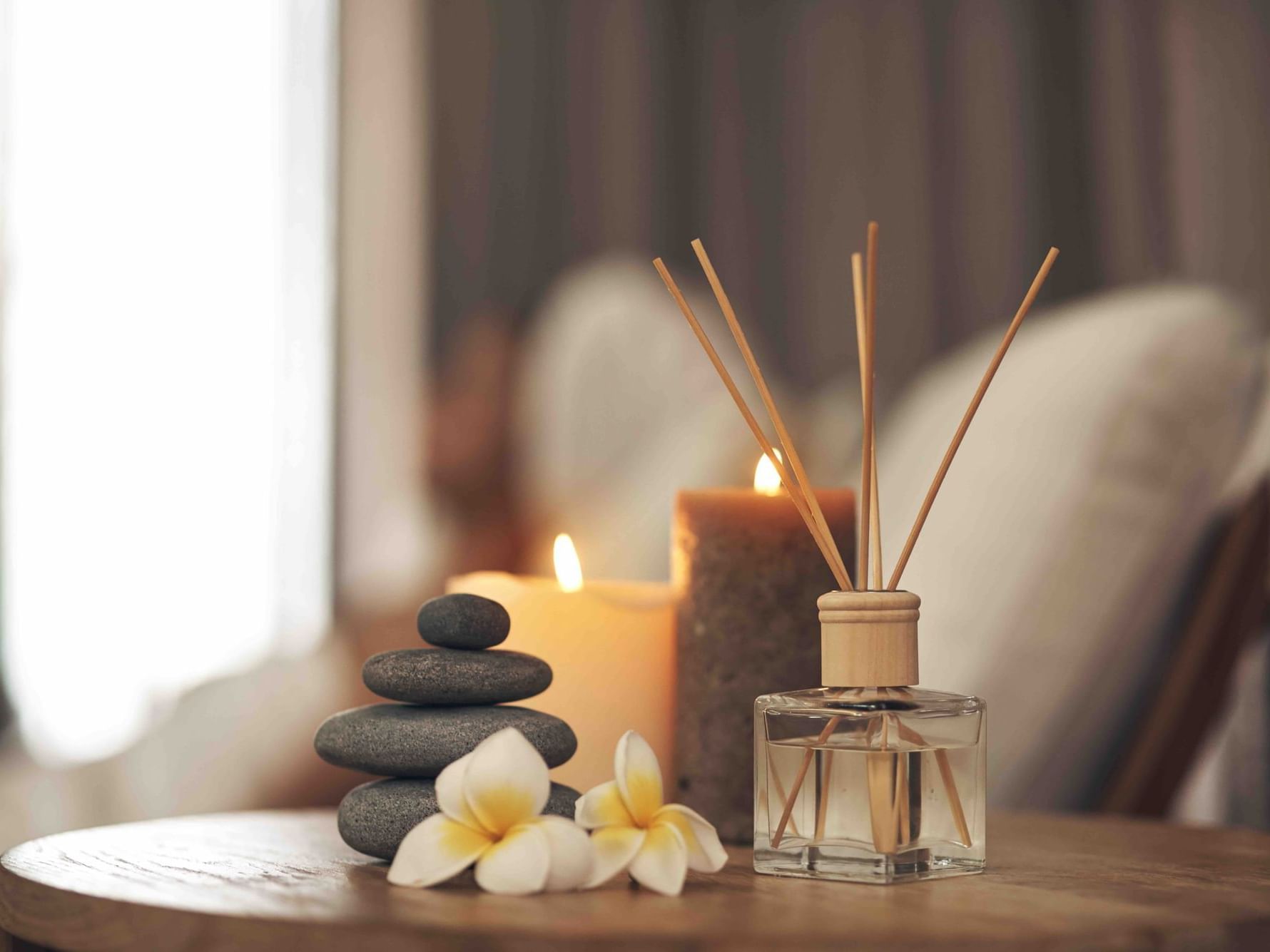 Close-up of lit candles, stones & essential oil on a table in The Spa at Danna Langkawi Hotel