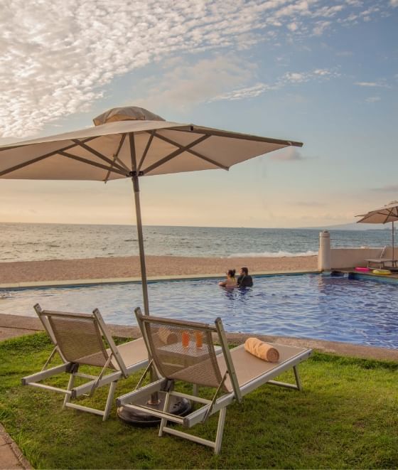 Poolside setup with two lounge chairs at Plaza Pelicanos Grand Beach Resort