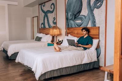 Man working with a laptop on a bed in Standard Double Room at Amaka Ocean Living Lodge