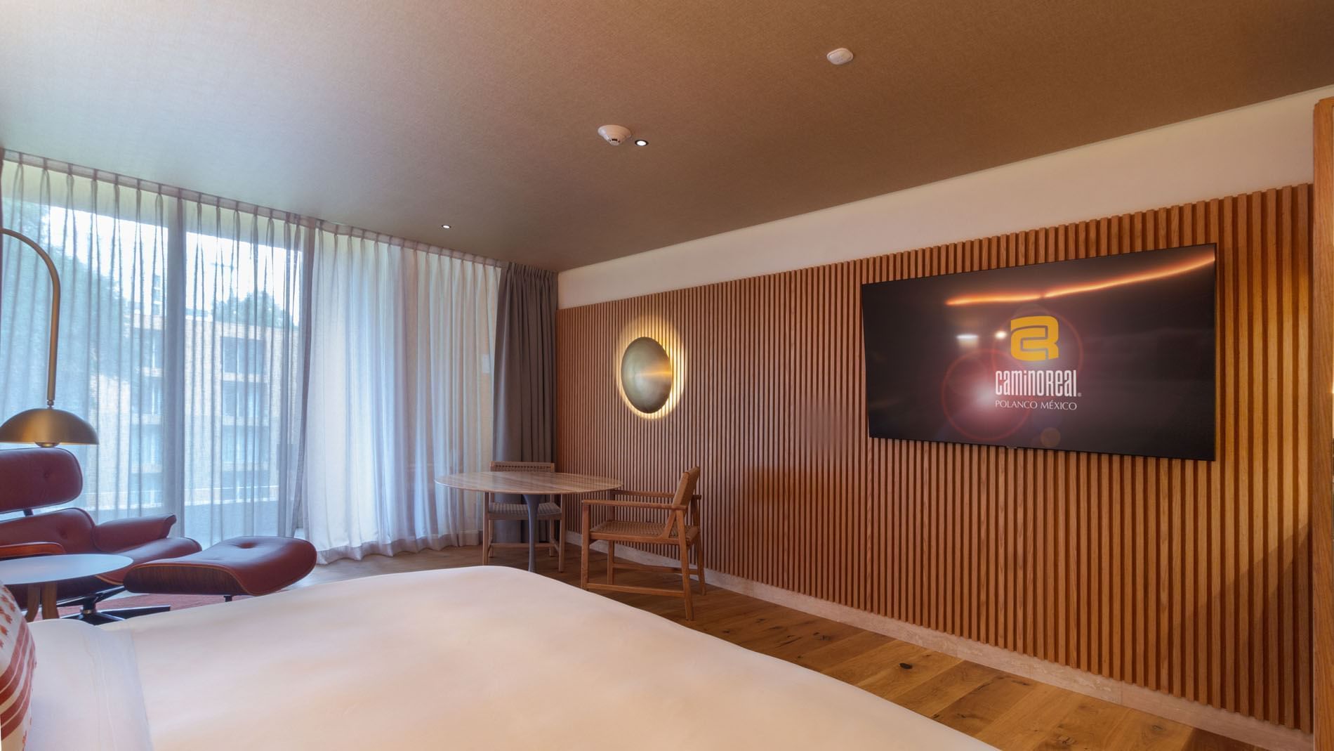 Habitación King Superior Camino Real Club con vista al jardín, pared de madera, luz y TV en Camino Real Polanco México