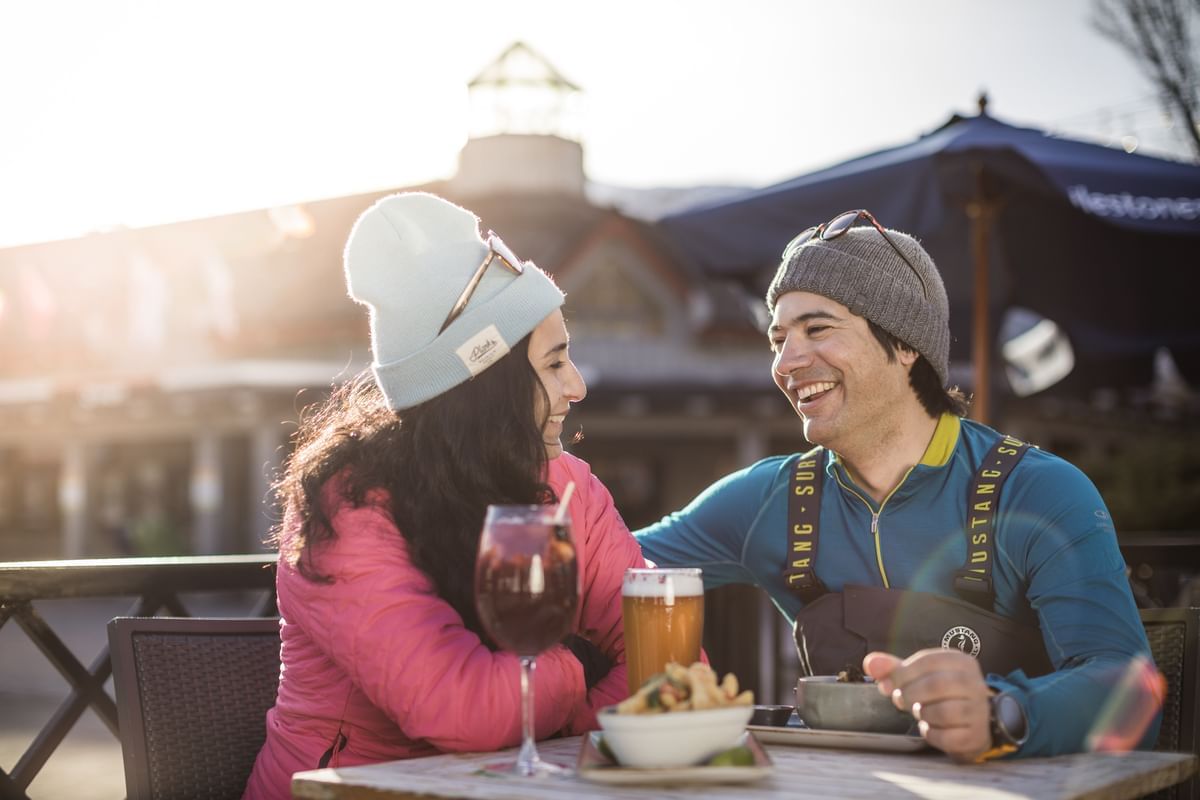 Couple hanging out in dining area outdoors at Blackcomb Springs Suites