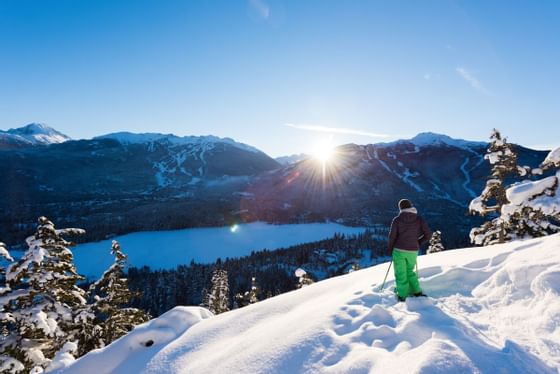 Person posing by a snow slope with skis near Blackcomb Springs Suites