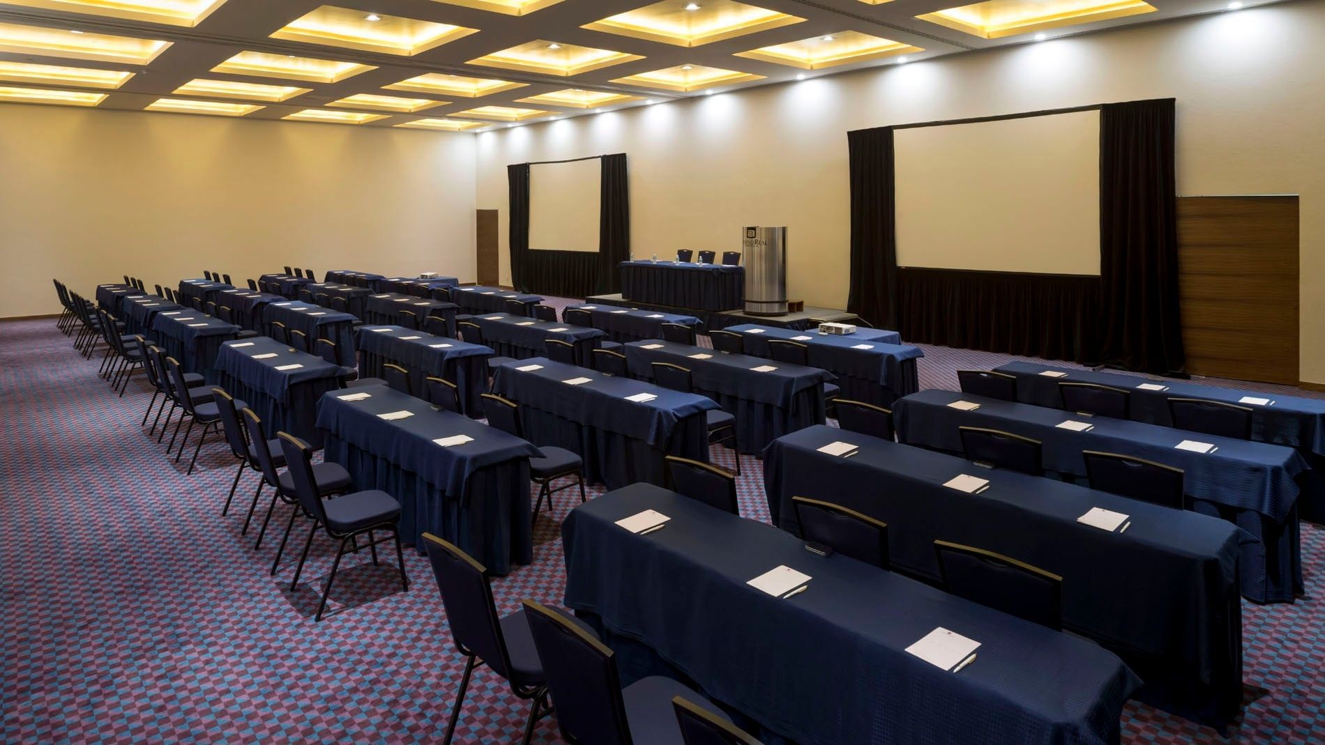 Gdl-Hmo theater-style event hall at Camino Real Pedregal Mexico, with neat rows of black chairs and gold ceiling