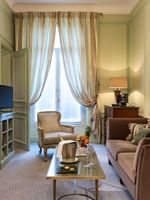 TV lounge with plush sofa near window in Deluxe Parisienne Suite at Hotel Westminster Paris