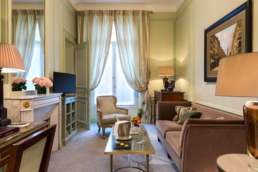 TV lounge with plush sofa near window in Deluxe Parisienne Suite at Hotel Westminster Paris