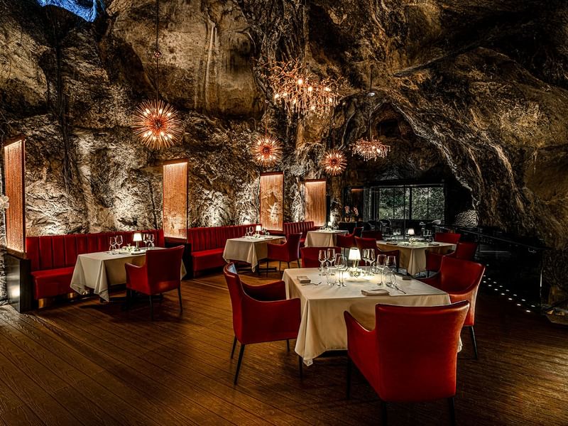 Jeff's Cellar cave dining area with red chairs and set tables in Ipoh at The Banjaran Hotsprings Retreat.