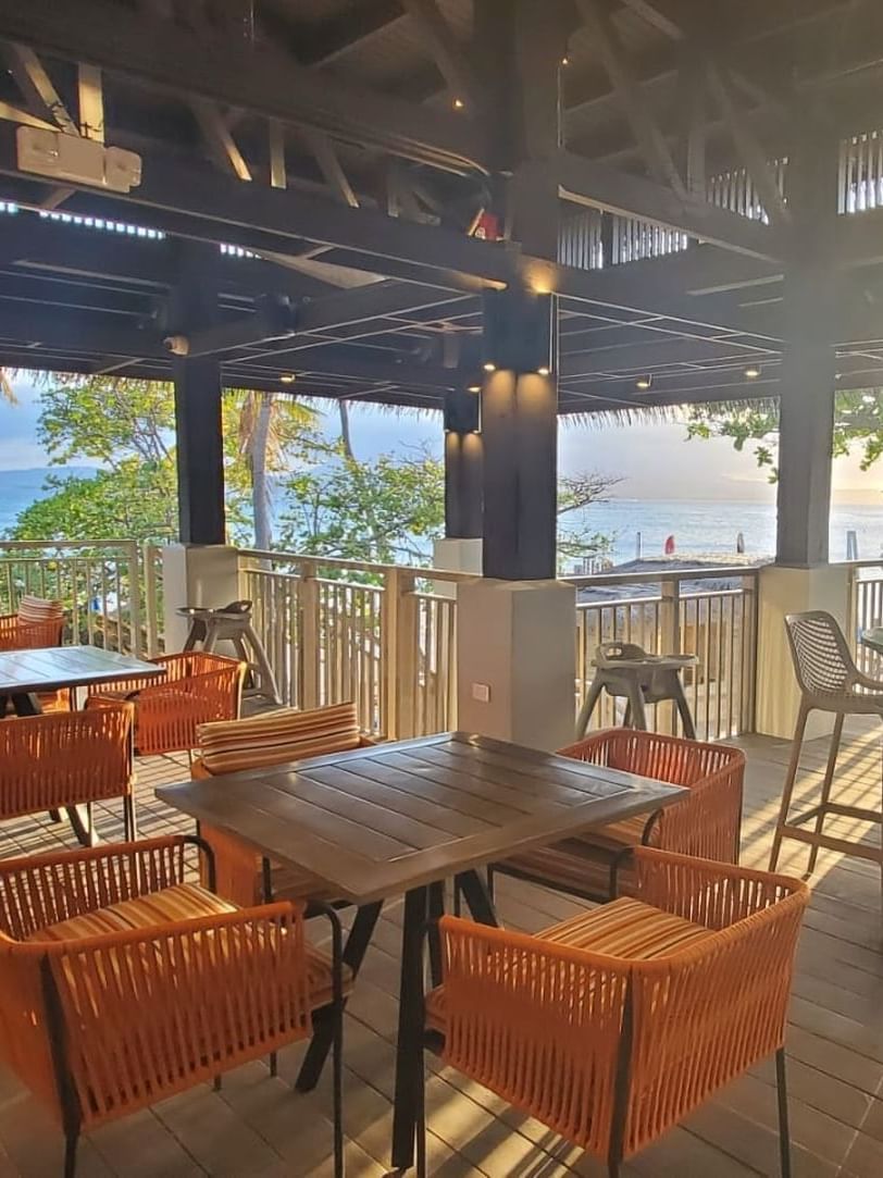 Palomino Bar & Restaurant with wooden tables and chairs, featuring a scenic view of the ocean at El Conquistador Resort
