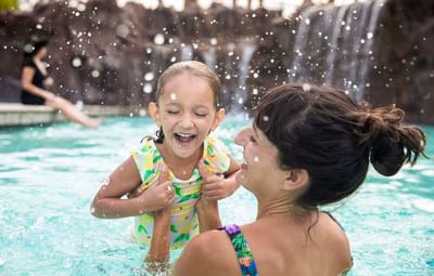 Daughter laughing with mom in swimming pool