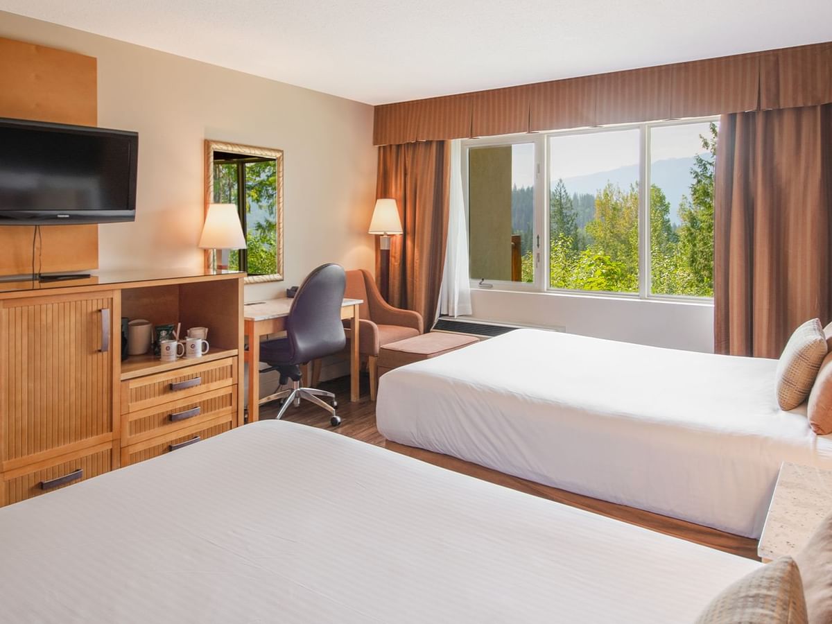 Hotel guest room with two queen beds, a work desk, TV, and arm chair