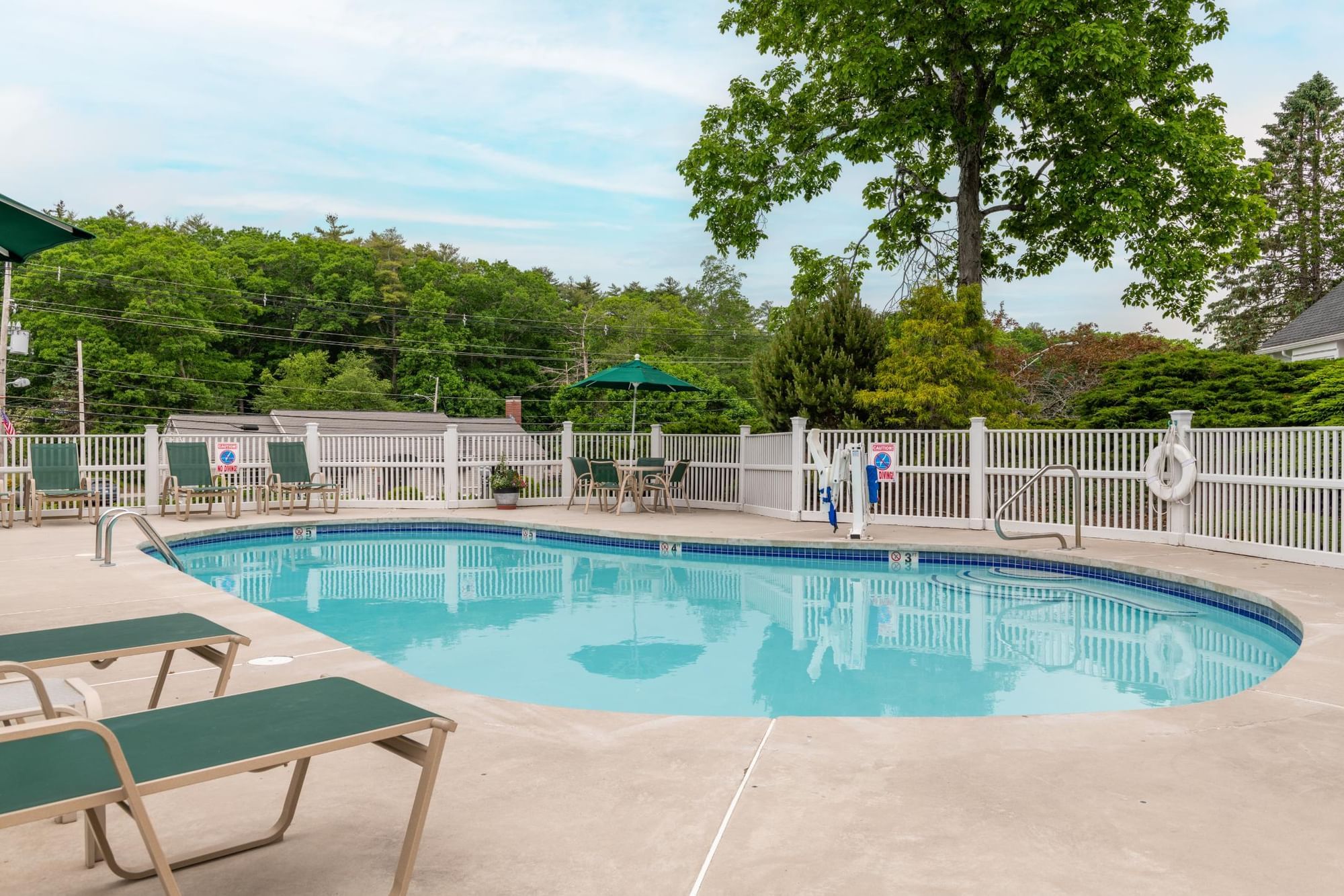 A serene outdoor pool area with lounge chairs and a fenced perimeter.