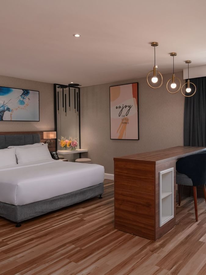King bed by a tall wooden bar table and two chairs in Executive Room City View at Warwick Al Jubail