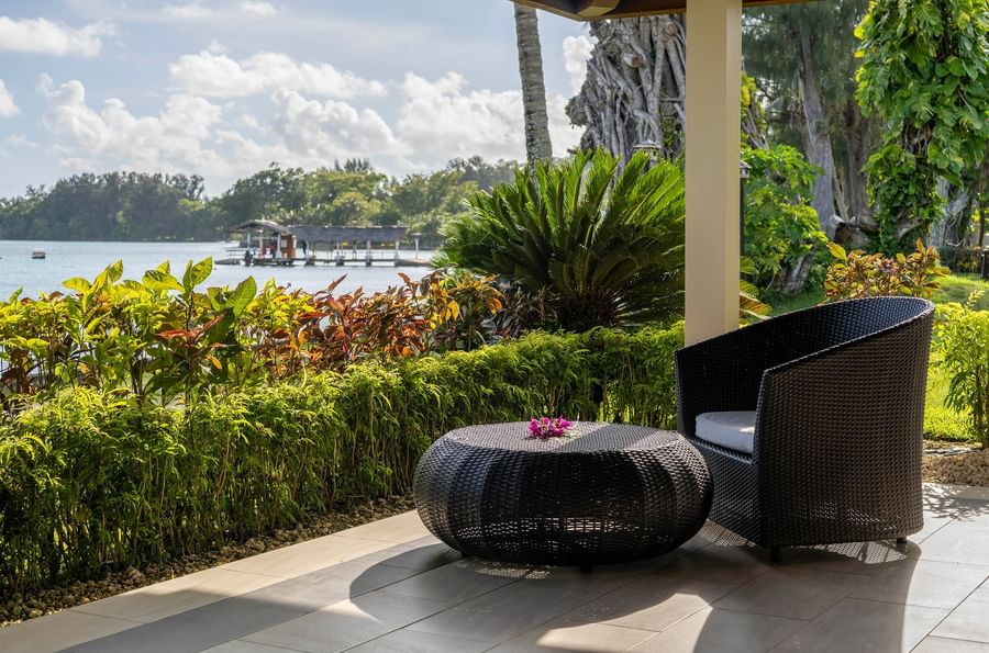 Patio area with wicker chair and table under the sun at Warwick Le Lagon.