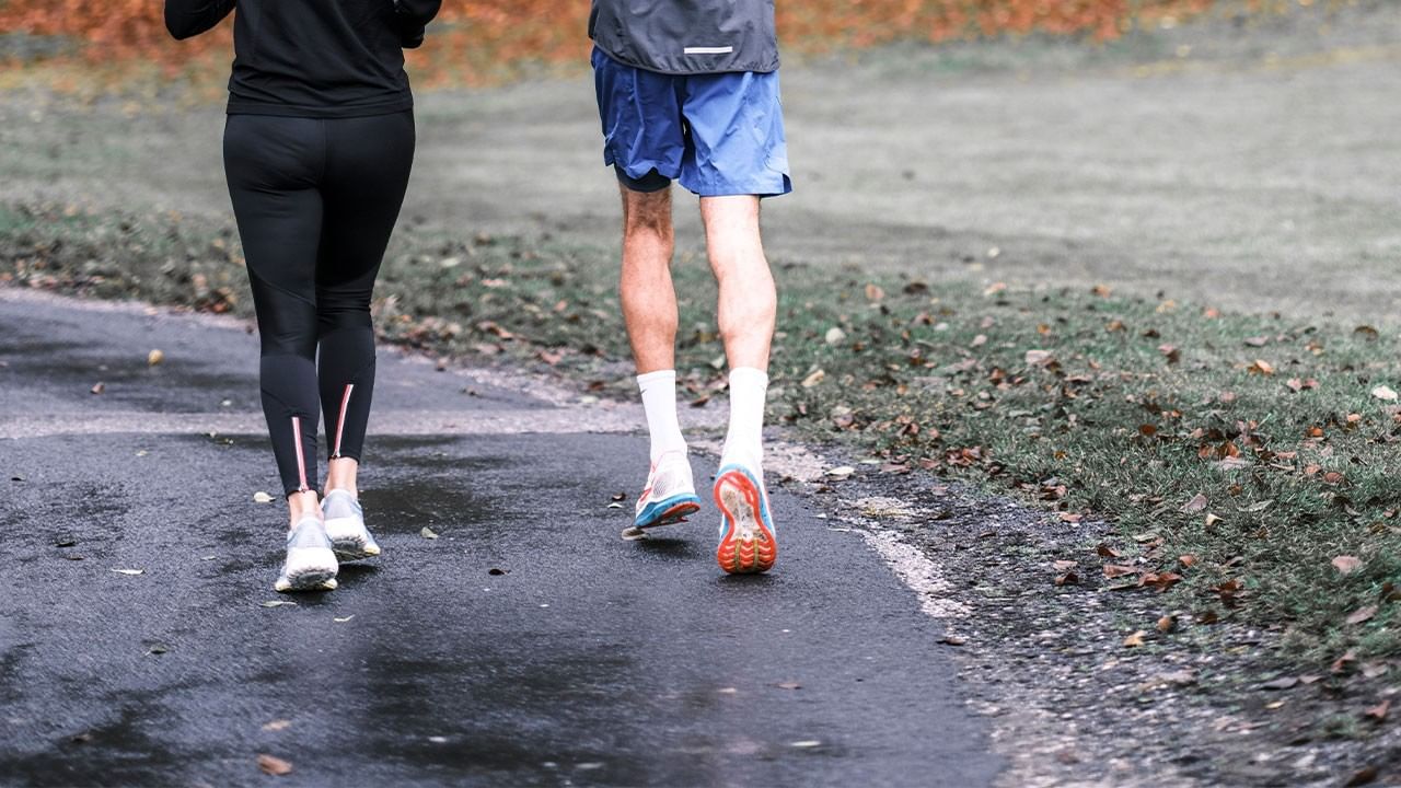 Due persone corrono su un sentiero umido, con un uomo in calzoncini blu e una donna in nero.