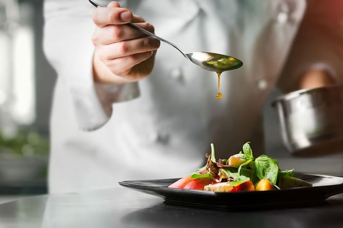 Close up of chef garnishing a fine dish served in a Restaurant at The Fullerton Hotel Sydney