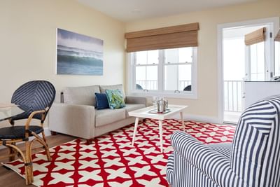 State Beach Pavilion Bed with a side table by the large windows and carpet floors in Winnapaug Pond at The Hotel Maria