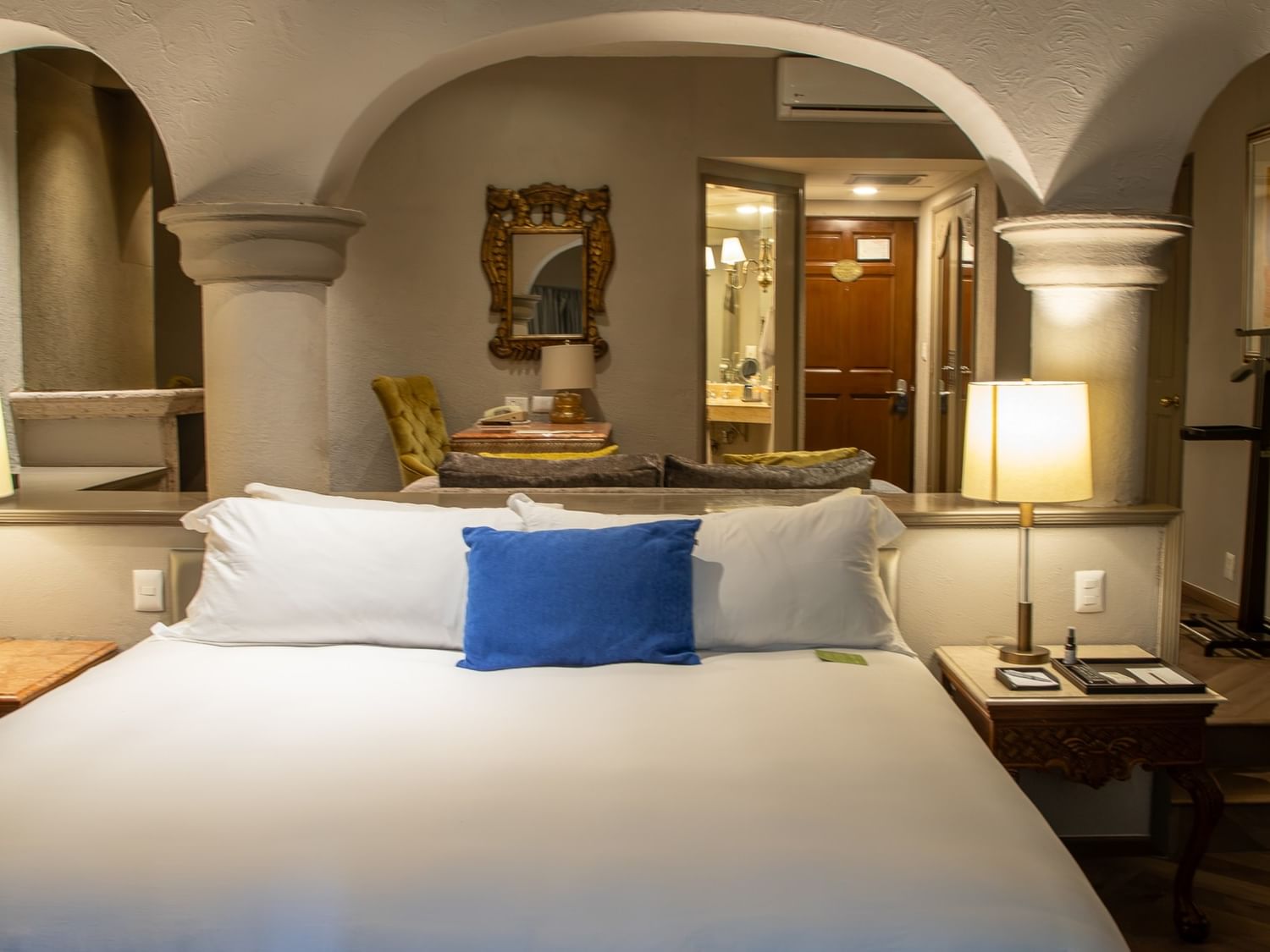 Master Suite King con cama king, arcos coloniales, mesas de noche con lámparas y área de estar en Quinta Real Guadalajara
