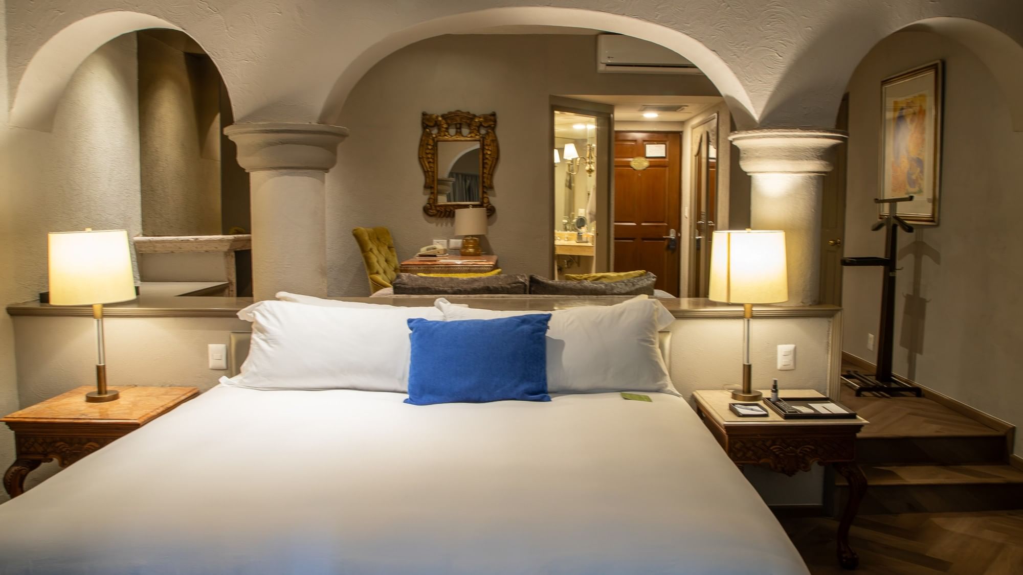Master Suite King con cama king, arcos coloniales, mesas de noche con lámparas y área de estar en Quinta Real Guadalajara
