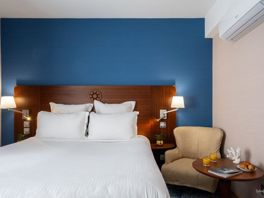 Chambre avec lit, fauteuil et table basse au Yachtman.