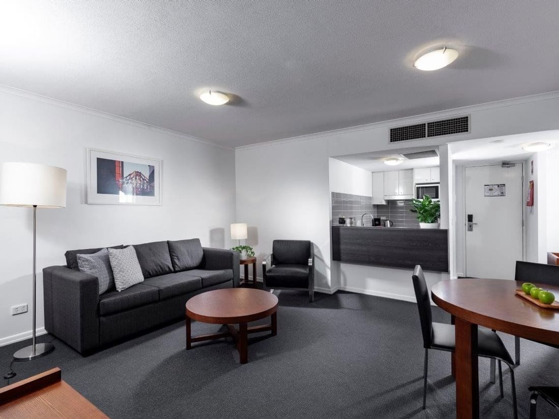 Two Bedroom Apartment with a dark sofa, a round dining table, and fully equipped kitchenette area at The Sebel Brisbane