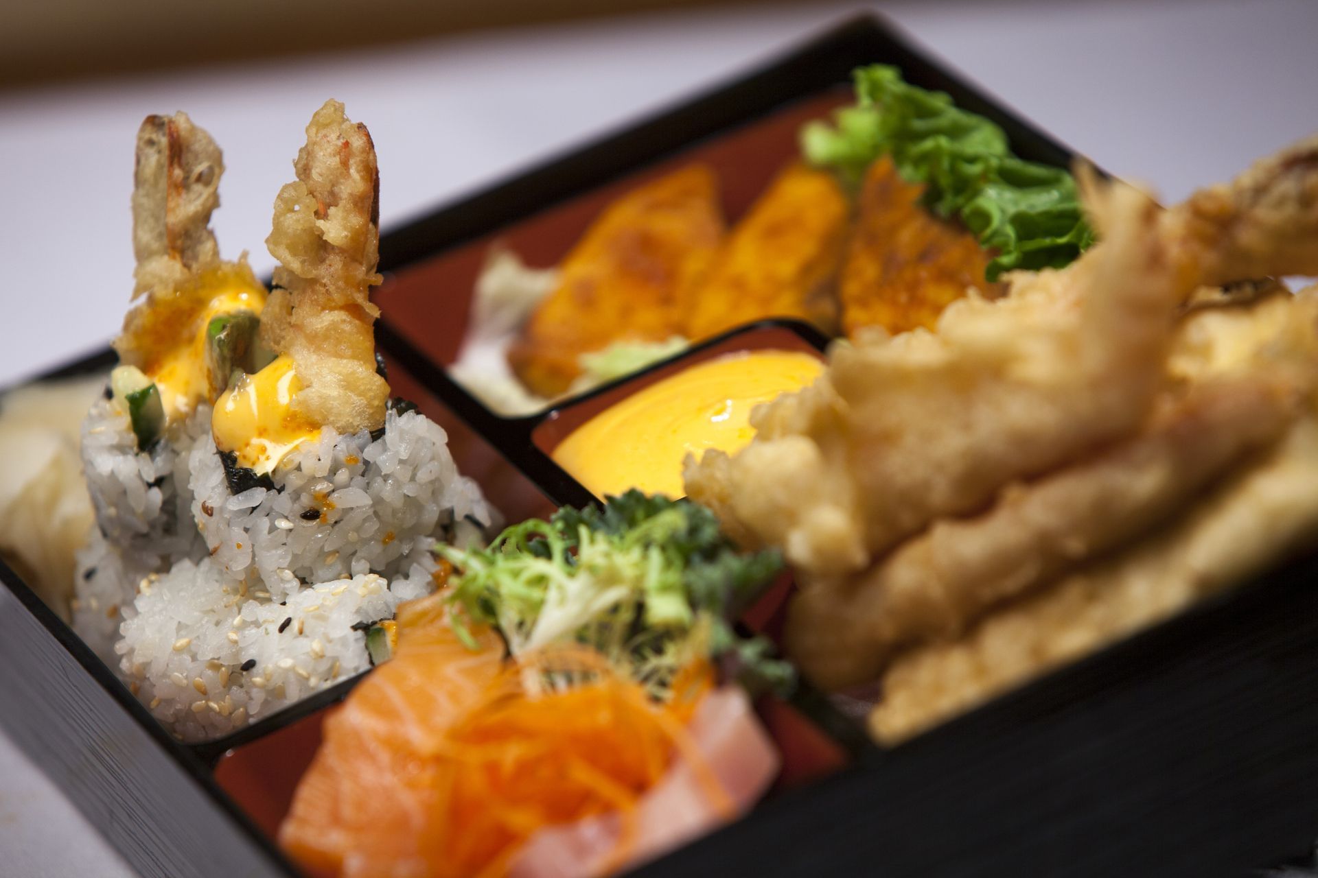 Bento box with shrimp tempura, sushi and ginger salad