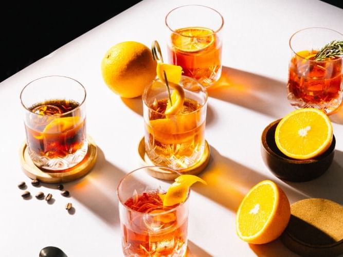 . A table with glasses of drinks and oranges, perfect for a refreshing summer gathering.