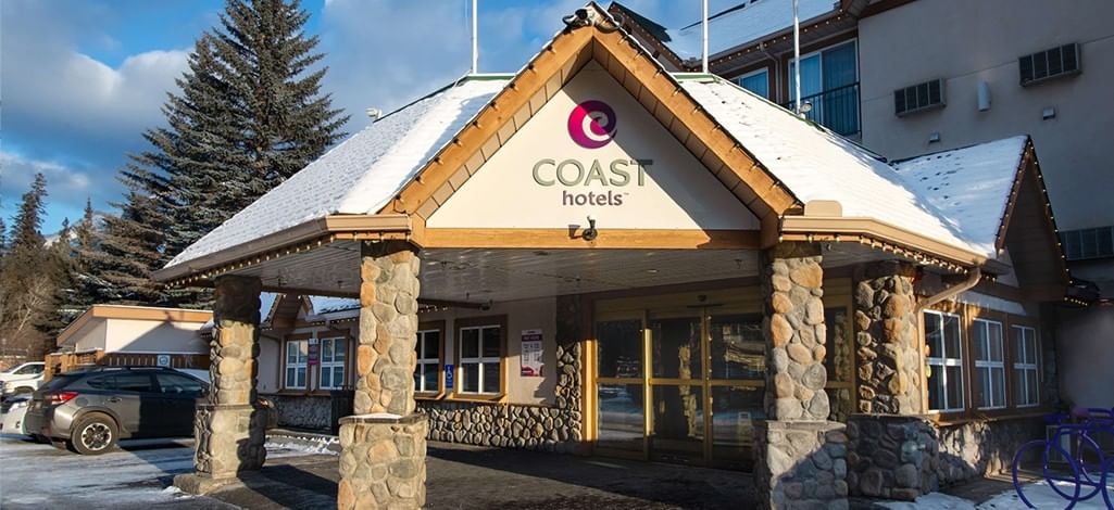 The entrance of the Coast Canmore Hotel & Conference Centre on a sunny winter day.