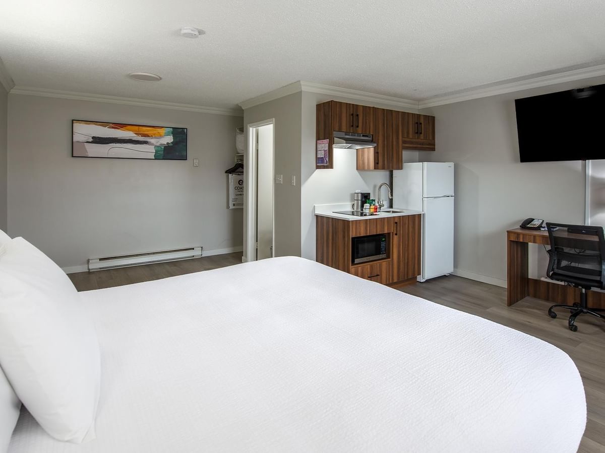 Hotel room with kitchen, desk, and TV at Coast Dawson Creek Hotel.