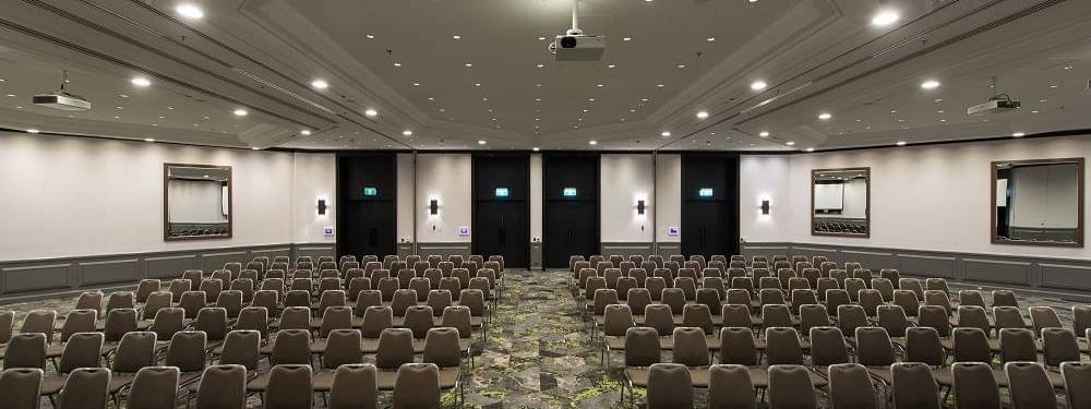 Theater-style setup under bright ceiling lights and carpet floors in Grand Ballroom at Novotel Sydney International Airport