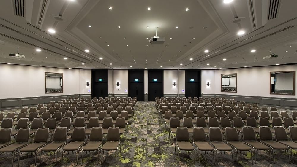 Theater-style setup under bright ceiling lights and carpet floors in Grand Ballroom at Novotel Sydney International Airport