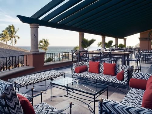 Lounge patio with black-and-white patterned sofas overlooking the ocean at Bar Santo Al Reves in Hacienda del Mar Los Cabos