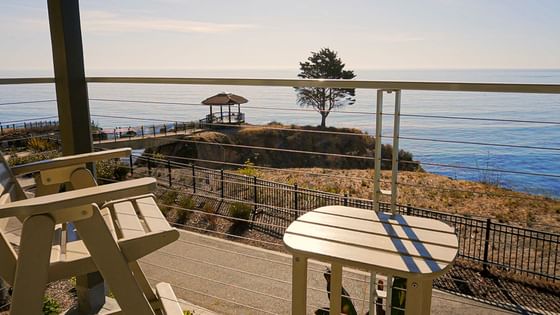 a wooden table and chair with ocean view 